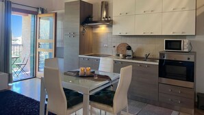 A modern kitchen with white cabinets, a microwave, and a built-in oven. - Venezia Golf Resort | Terrace & Free Parking (Martellago)
