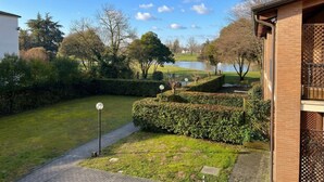 A residential area with a lawn, a pathway, and a body of water in the background. - Venezia Golf Resort | Terrace & Free Parking (Martellago)