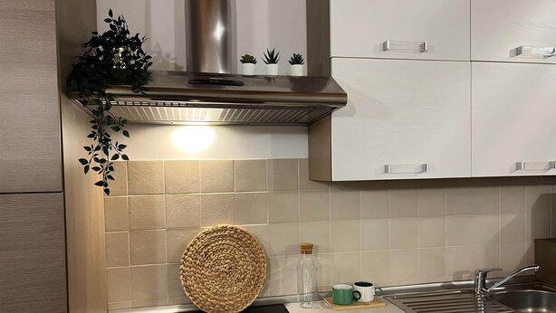 A kitchen with a stainless steel range hood, a built-in oven, a sink with a faucet, and cabinets. - Venezia Golf Resort | Terrace & Free Parking (Martellago)
