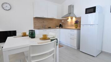 Une cuisine moderne avec des meubles blancs, un four à micro-ondes et une horloge au mur.