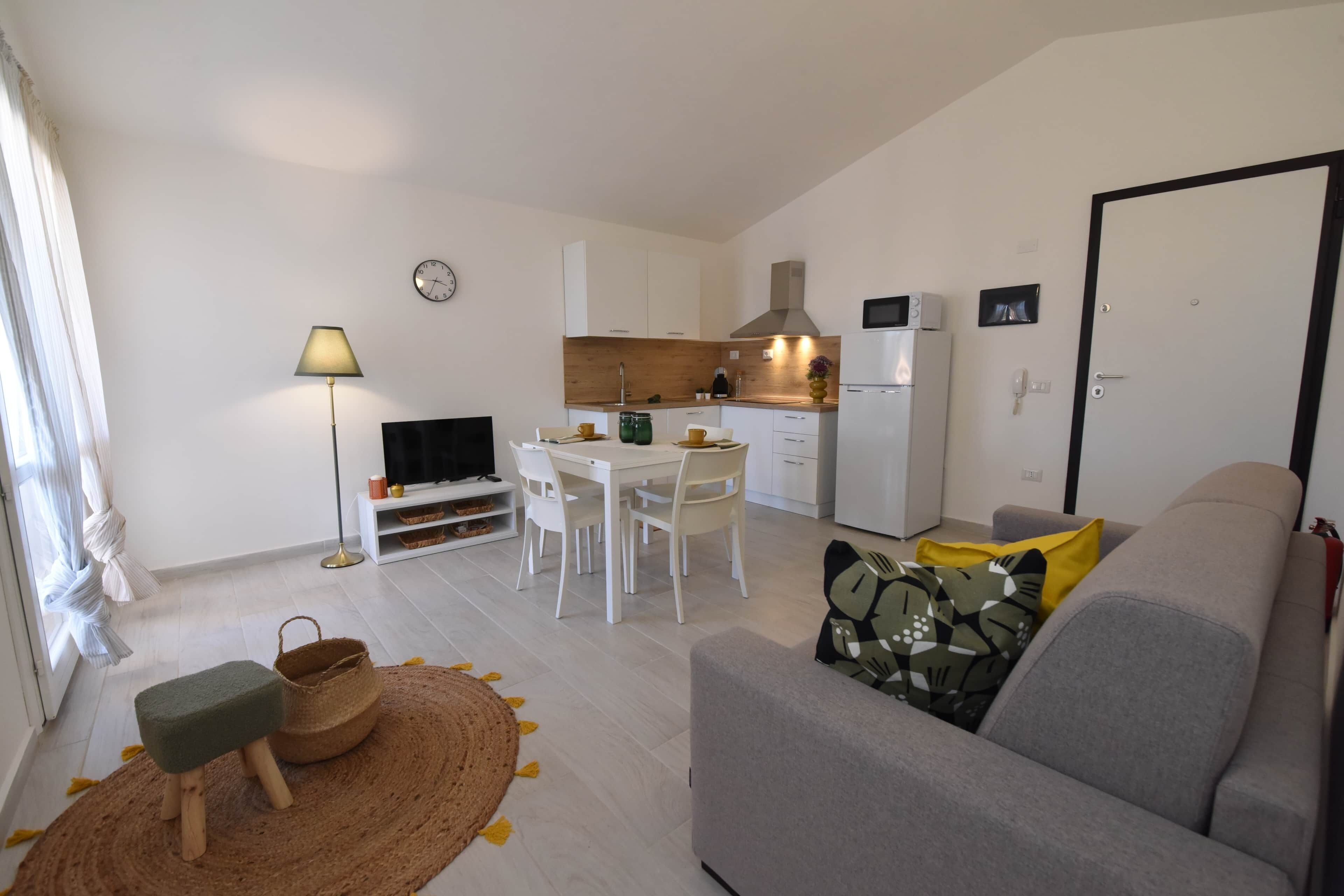 Un espacio habitable compacto con kitchenette, comedor, sofá y televisor.