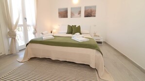 Ein Schlafzimmer mit Bett, Nachttischen, einer Lampe und Blick ins Freie.