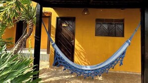 A yellow building with a tiled roof, a hammock, and a door labeled 'X4pa'. - Room-nice and Cozy Room With Pool (São Miguel do Gostoso)