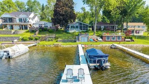 Una marina con barcos amarrados, un muelle flotante con sillas y casas al fondo.