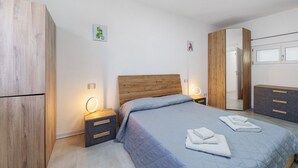 Ein Schlafzimmer mit einem Bett, Nachttischen, einem Kleiderschrank und einem Spiegel.