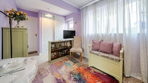 Ein Wohnzimmer mit einer Couch, einem Fernseher, einem Teppich mit Muster und einem Schrank.