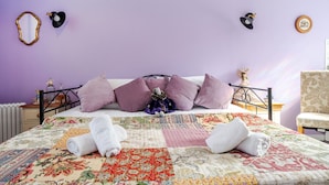 Ein ordentlich bezogenes Bett mit einer Blumensteckdecke, einem kleinen Plüschtier und zwei aufgerollten Handtüchern an der Kopfteil.