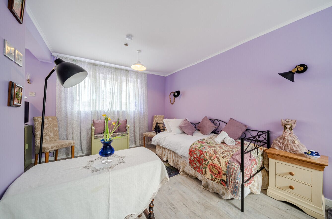 Une chambre à coucher comprenant un lit, une table de chevet, une lampe, une chaise et une commode.