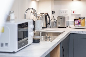 A modern kitchen with a microwave, toaster, kettle, and a coffee maker.