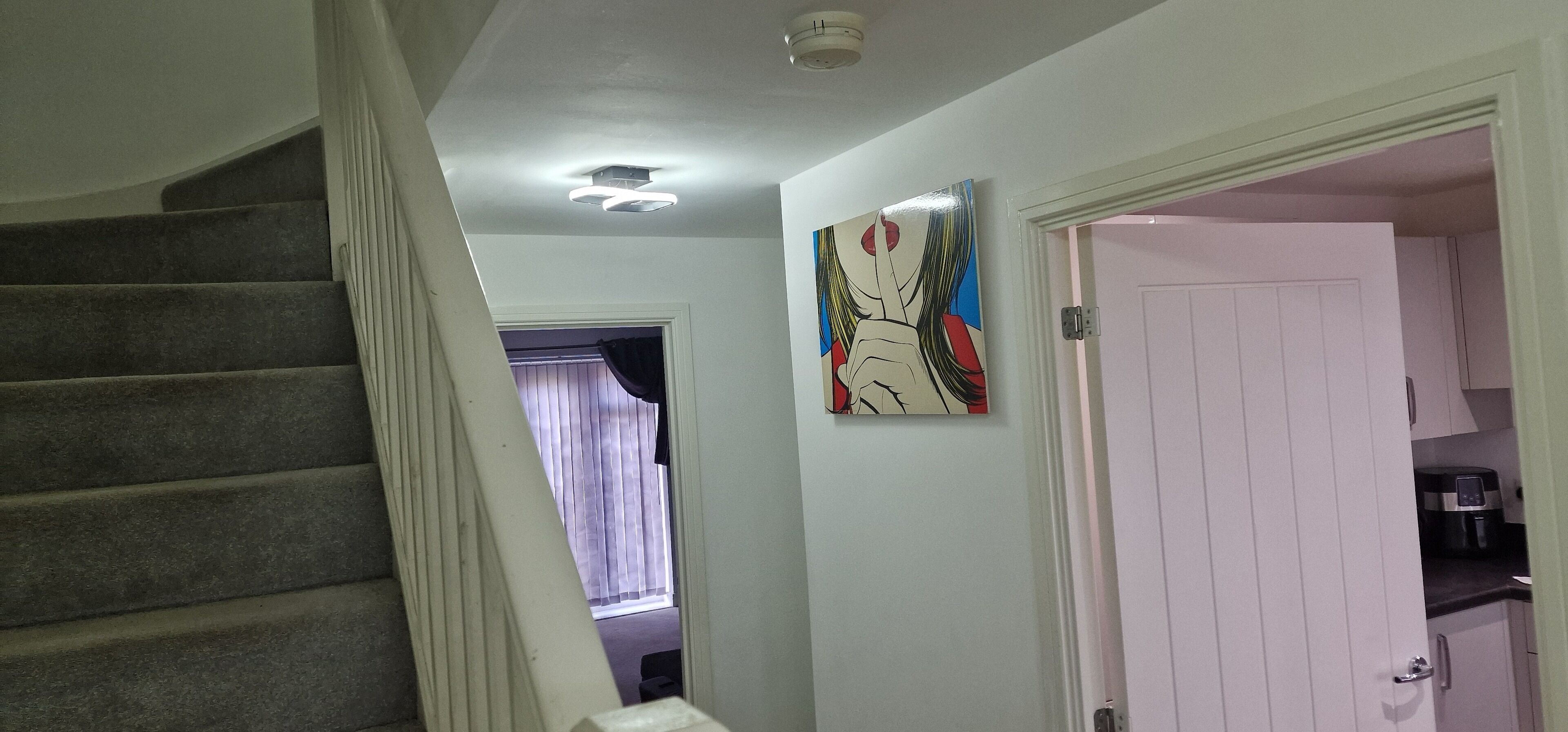 A staircase, a door, and a painting in a hallway.