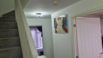 A staircase, a door, and a painting in a hallway.