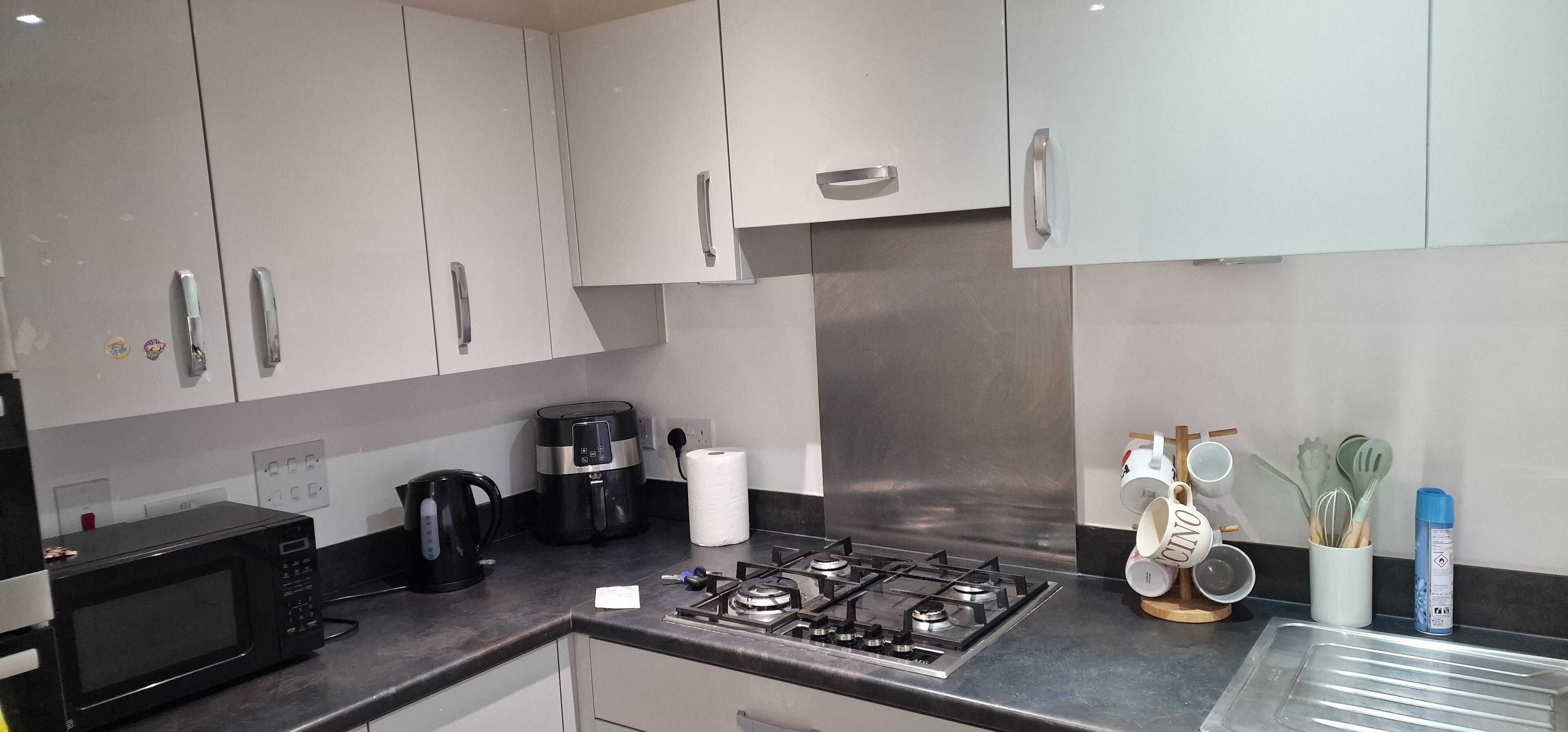 A modern kitchen with stainless steel appliances, white cabinets, and a gas stove.