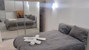 A bedroom with a bed, a mirror, a painting, and a wardrobe.