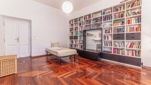 A room with a bed, a wooden floor, a bookshelf, and a white door. - Casa Anna - Vatican City  (Rome)