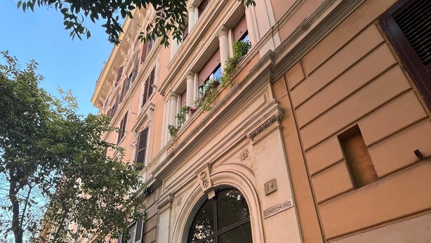 A building with a large arched entrance, a balcony with plants, and a sign indicating it is a condominium. - Casa Anna - Vatican City  (Rome)