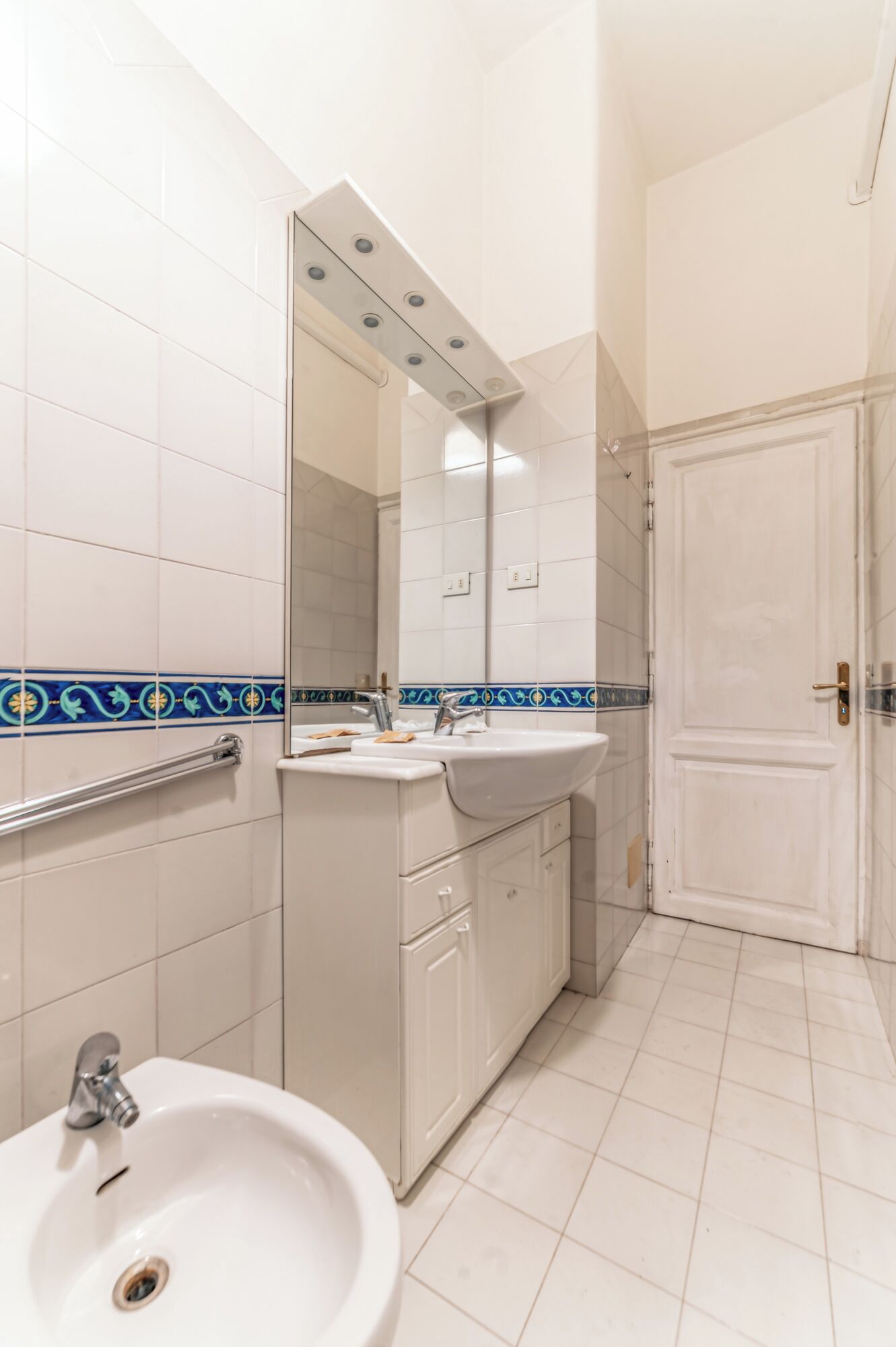 Et badeværelse med vask, spejl og toilet.