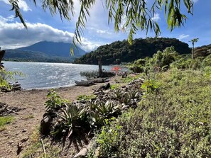 Un paisaje natural con un lago, vegetación y una montaña al fondo.