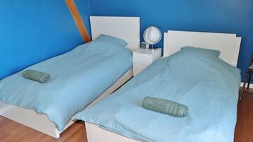 Deux lits jumeaux avec une parure de lit bleue assortie et une petite table de chevet avec un miroir.