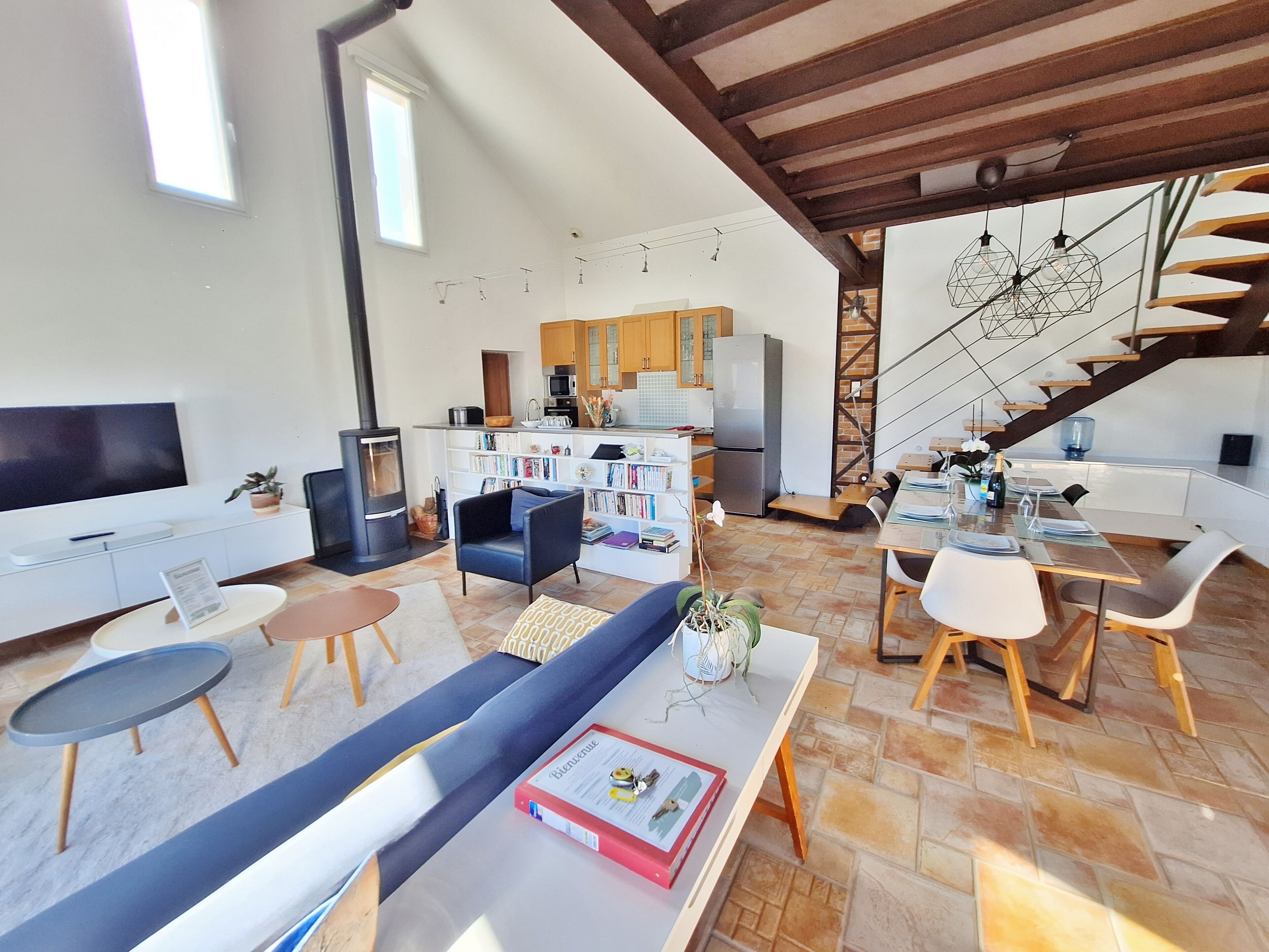 Ein stilvoller Wohnraum mit Sofa, Esstisch, Küche und einer Treppe.