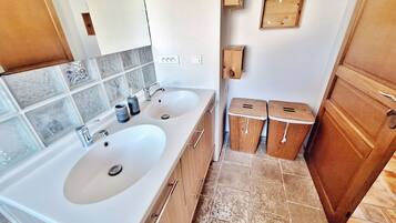 A bathroom with two sinks, a mirror, a towel rack, and a wooden door.