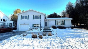 A two-story house with a garage, a front porch, and a snow-covered yard. - Room-saint John - Wi-fi - 4mins Regional (Saint John)