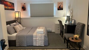 A neatly arranged bedroom with a bed, desk, chair, and a small table with a flower vase. - Room-saint John - Wi-fi - 4mins Regional (Saint John)