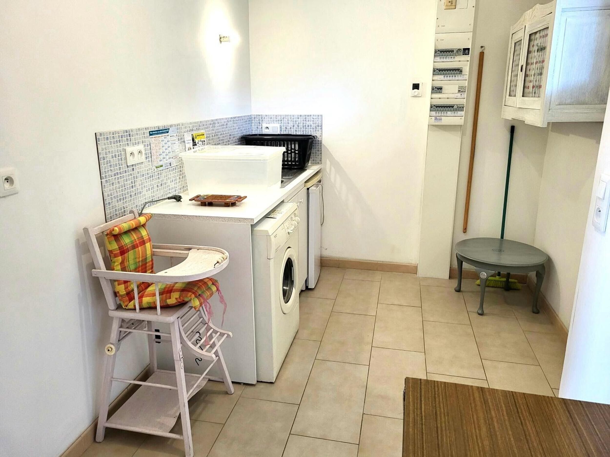 Un área de lavandería con lavadora, secadora y una pequeña mesa con una silla.