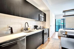 A modern kitchen with dark cabinetry, a stainless steel range, and a built-in oven. - Downtown Miami Studio w/ City Views (Miami)