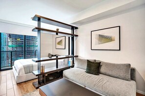Ein modernes Wohnzimmer mit einer Couch, einem Couchtisch und einem großen Fenster mit Blick auf eine Baustelle.