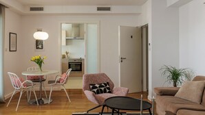 Un soggiorno moderno con zona pranzo, una cucina sullo sfondo e una porta che dà su un'altra stanza.