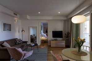 Ein modernes Wohnzimmer mit Sofa, Sesseln, Couchtisch und einem Essbereich mit Tisch und Stühlen.