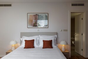 Ein Hotelzimmer mit einem Bett, zwei Nachttischen, einem Wandbild und einer Tür zu einem Badezimmer.