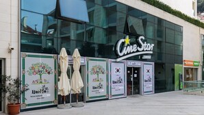 Un cinema CineStar con ampie vetrate, un cartello pubblicitario e manifesti promozionali di cucina coreana.