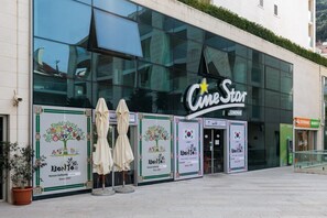 Ein CineStar-Kino mit großen Glasschaufenstern, einer Schautafel und Werbeplakaten für koreanische Küche.