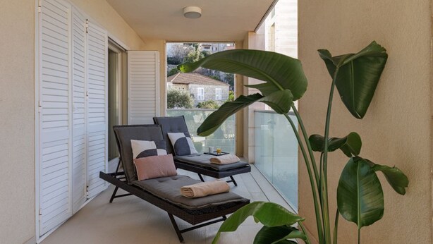Un balcone con due poltrone, un'ampia pianta e vista sugli edifici.