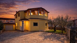 Uma casa de dois andares com varanda, garagem e entrada de pedra.