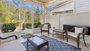 Eine Terrasse im Freien mit Korbmöbeln, einem Glastisch und einem Deckenventilator.