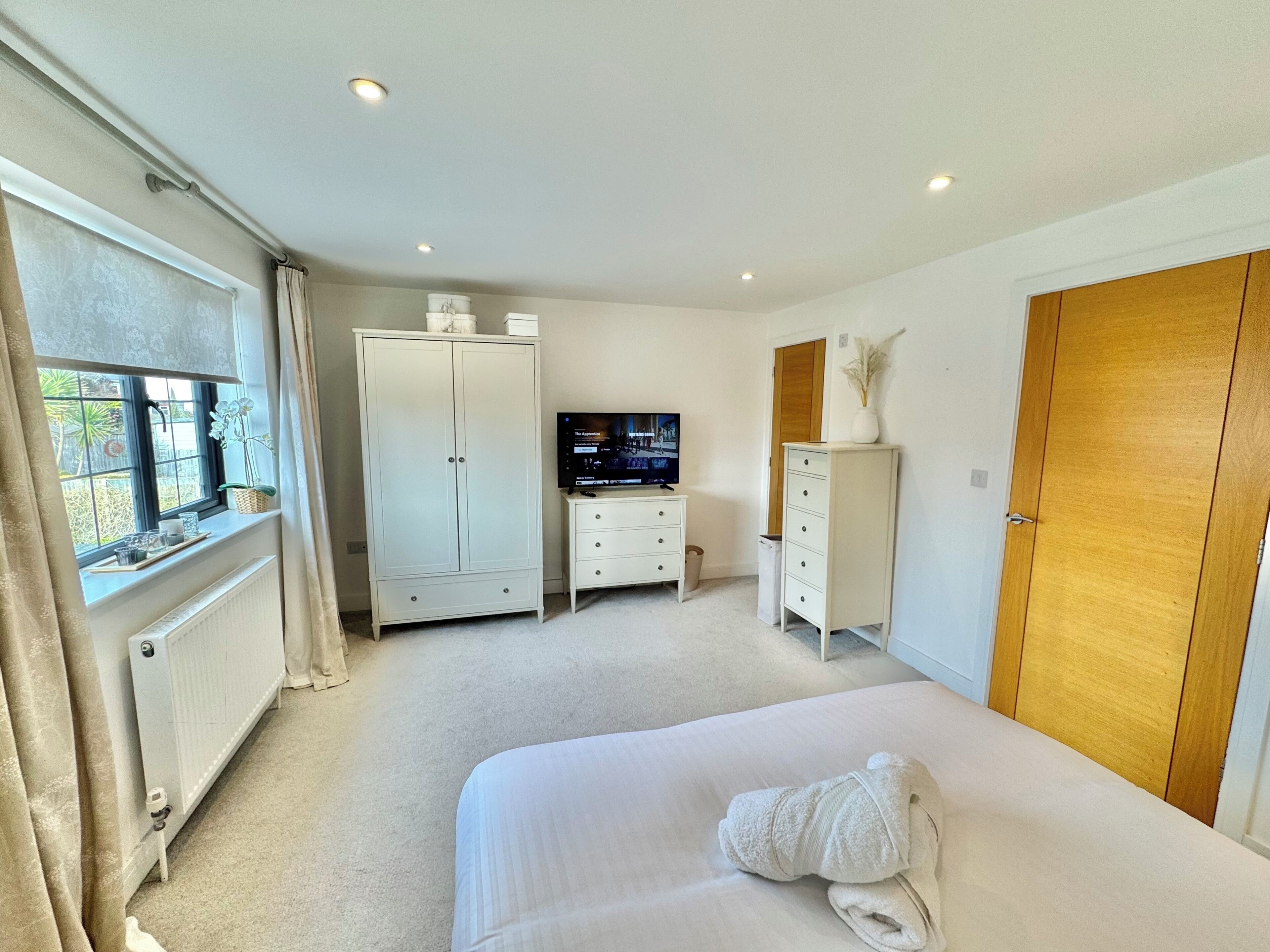 A bedroom with a bed, a TV, a wardrobe, and a radiator.