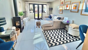 A modern living room with a fireplace, a sofa, a coffee table, and a patterned rug. - Modern Luxury Home - Hot Tub - 3 King Bedrooms - Free Parking - Close to Beaches (Poole)