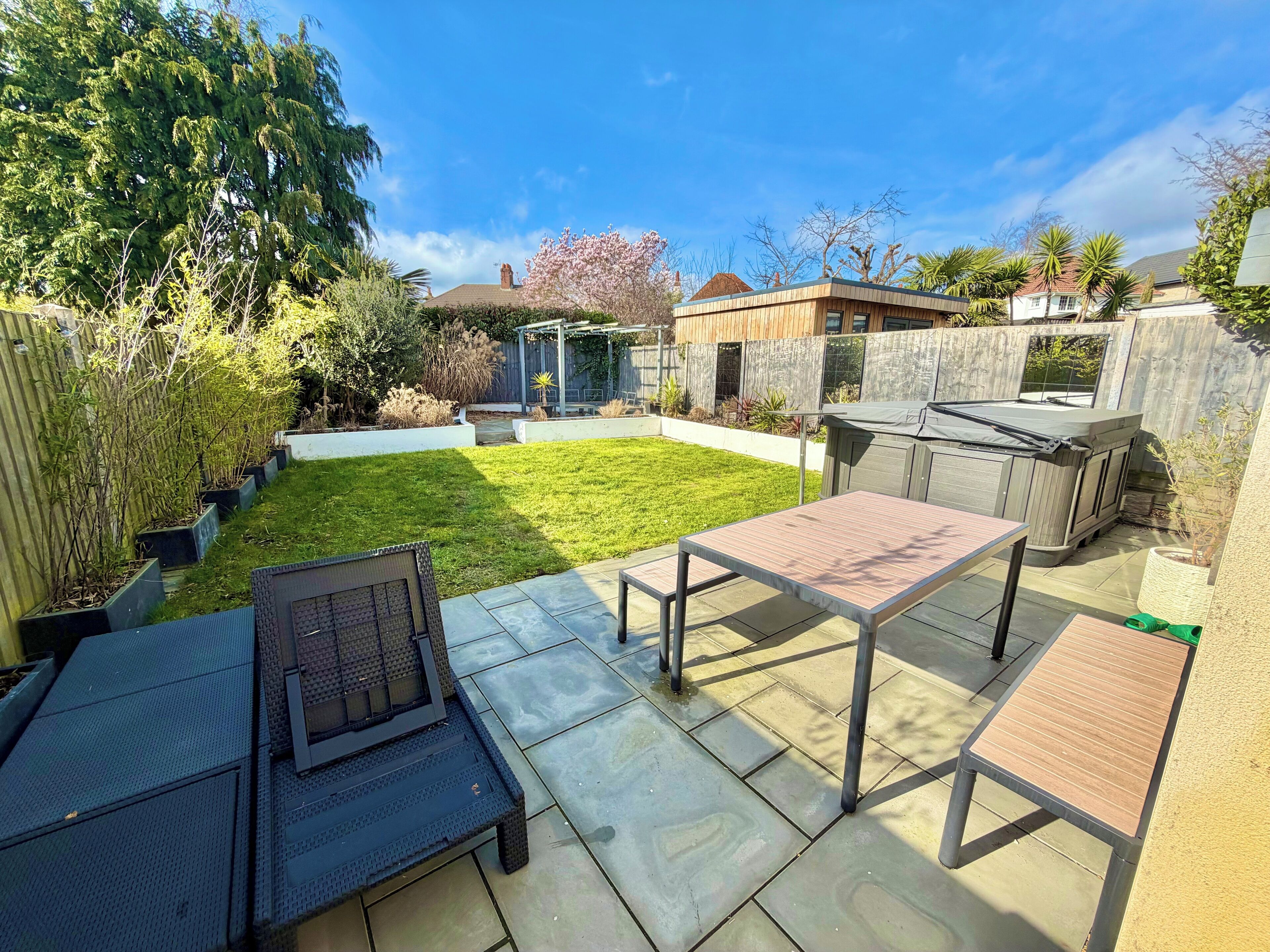 Un jardin avec une terrasse, un espace barbecue et un petit potager.