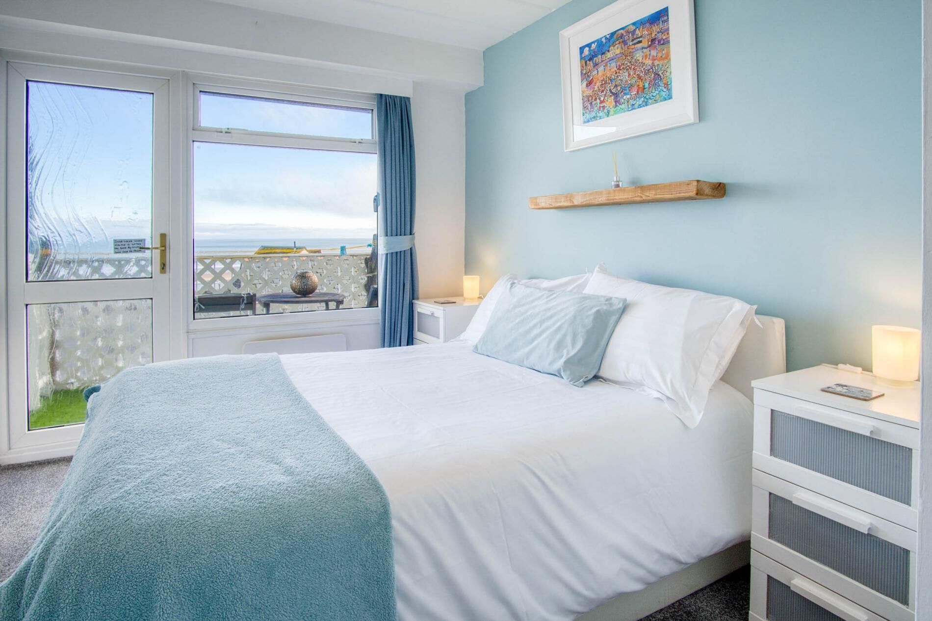 A bedroom with a bed, nightstands, a window with a view, and a wall-mounted shelf.