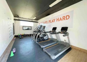 Une salle de sport équipée de tapis de course, d’un mur orné de citations motivantes et de matériel d’exercice.