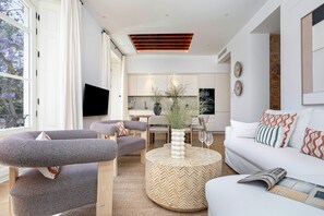 A modern living room with a sofa, armchairs, a coffee table, and a dining area in the background. - Elegant 3BD apartment in Malaga. Plaza Marina II (Malaga)