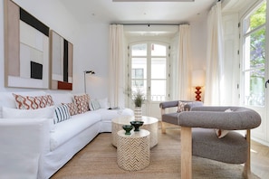 Een moderne woonkamer met een witte bank, een ronde salontafel en een grijze fauteuil.