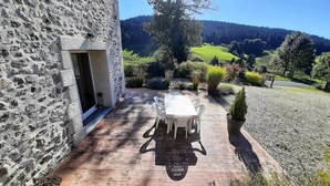 Ein Steingebäude mit Terrasse, Tisch und Stühlen im Freien.