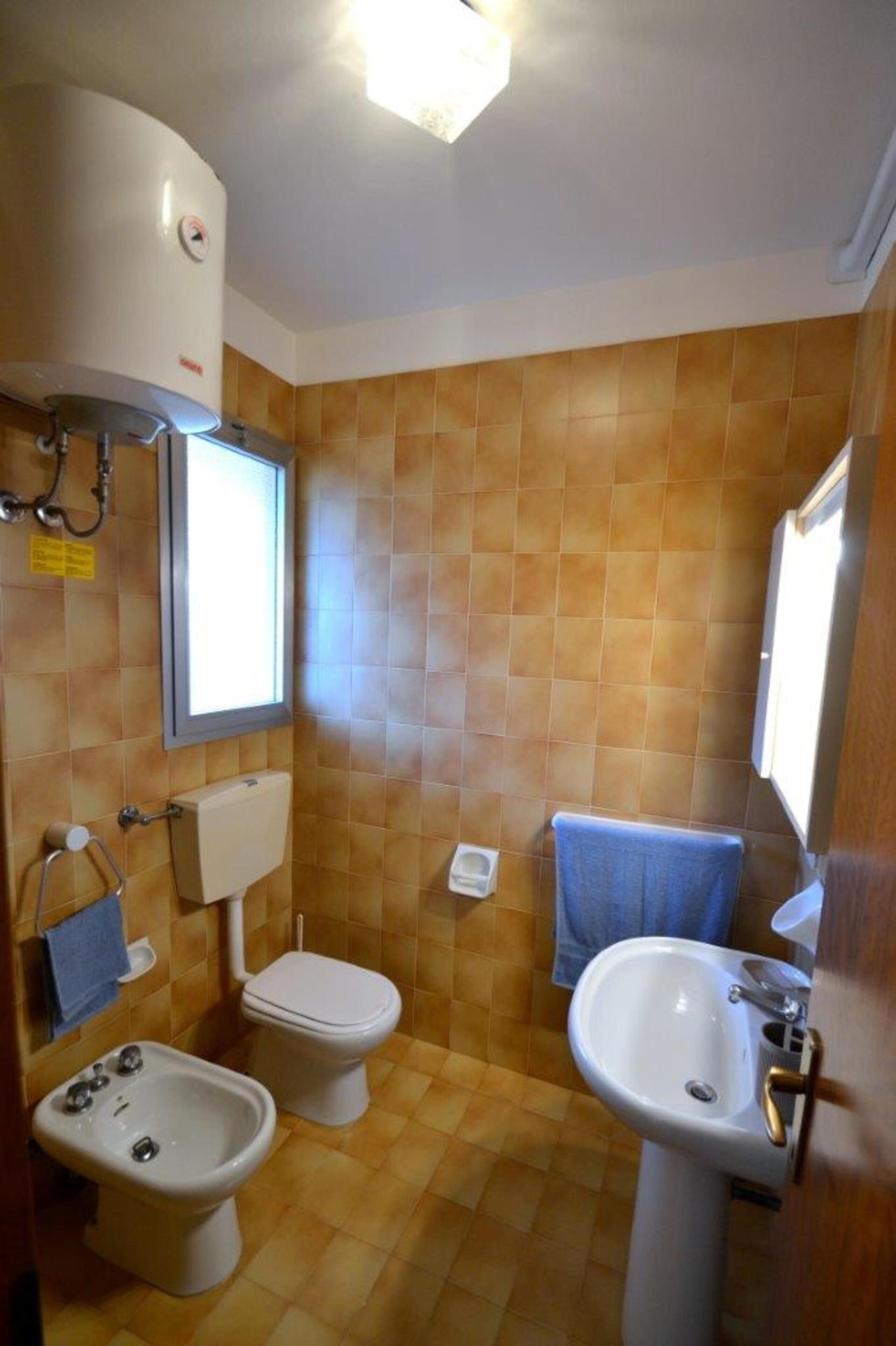 Un bagno con toilette, bidet, lavandino e una finestra.