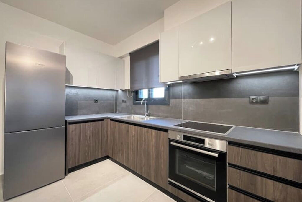 A modern kitchen with stainless steel appliances, wooden cabinetry, and a sleek countertop.