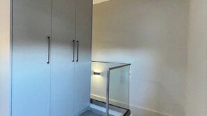Um interior moderno com divisória de vidro, guarda-roupa branco e luminária.