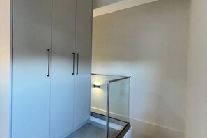 Ein modernes Interieur mit Glastrennwand, weißem Kleiderschrank und einer Leuchte.