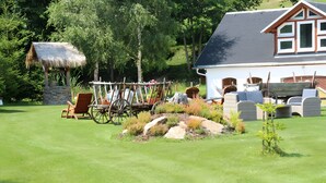 Ein Haus mit einem strohgedeckten Gebäude, einem Holzwagen und Gartenmöbeln.